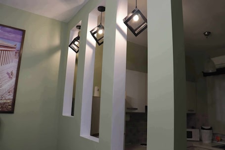 A room with a green wall, a framed picture, and a kitchen area with a microwave.. Anemi Leros Apartments