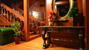 Una escalera de madera con un banco verde, una consola de madera con un espejo y un jarrón con flores.