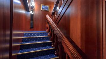 A wooden staircase with blue carpeted steps and a wooden handrail.