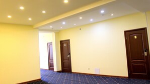 A hotel corridor with three doors, a carpeted floor, and recessed ceiling lights.