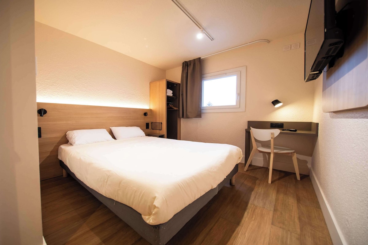Une chambre d’hôtel avec un lit, un bureau et une chaise.