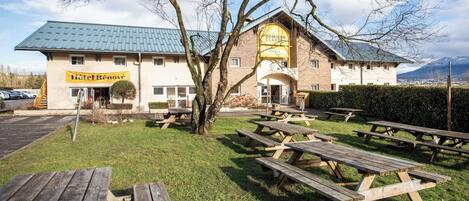 A hotel with outdoor picnic tables and a parking lot.