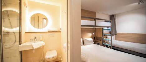 A modern hotel room with a bathroom, a bed, and a bunk bed.