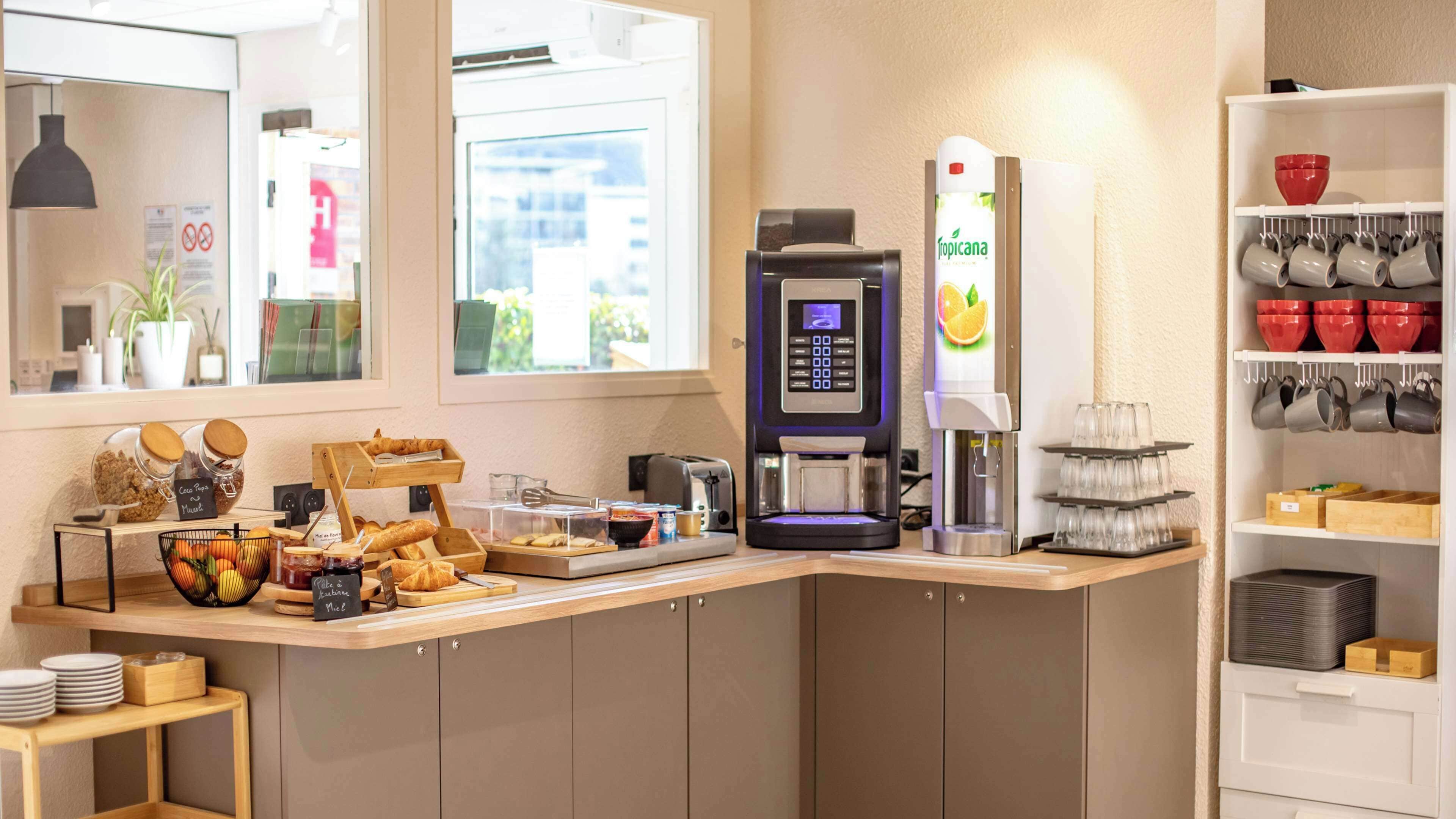 Een ontbijtbalk met een koffieapparaat, een fruitschaal en een plank met mokken en kommen.