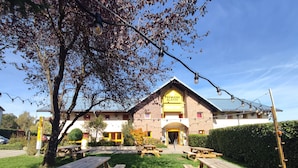 A hotel with a prominent entrance, outdoor seating, and a well-maintained lawn.