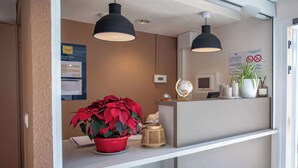 A reception desk with a red potted plant, a globe, candles, and a sign indicating no smoking.