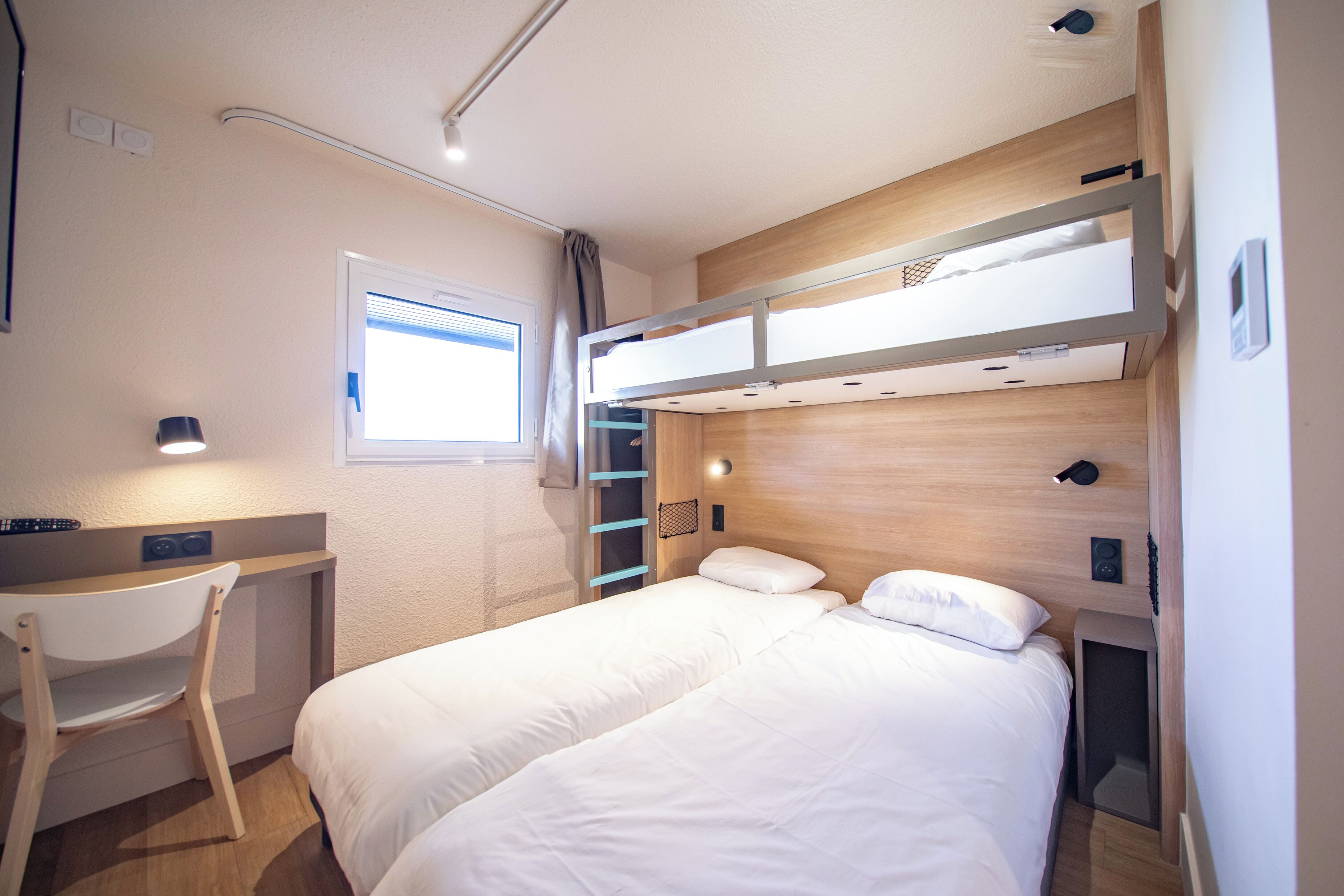 Une chambre à coucher de taille réduite, équipée d’un lit superposé, d’un bureau et d’une chaise.