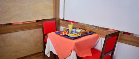 A dining area with a table set for breakfast, including a fruit platter, a croissant, and a glass of juice.
