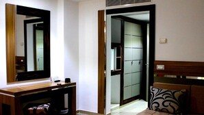 A hotel room with a wooden desk, a large mirror, a sofa with patterned cushions, and a sliding door leading to a bathroom. - Hotel Marina Prestige Tabarka (Tabarka)