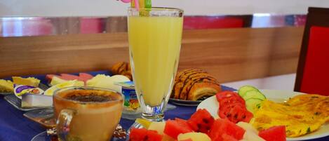 A breakfast setting with a variety of food items including a croissant, omelette, watermelon, and a glass of orange juice.
