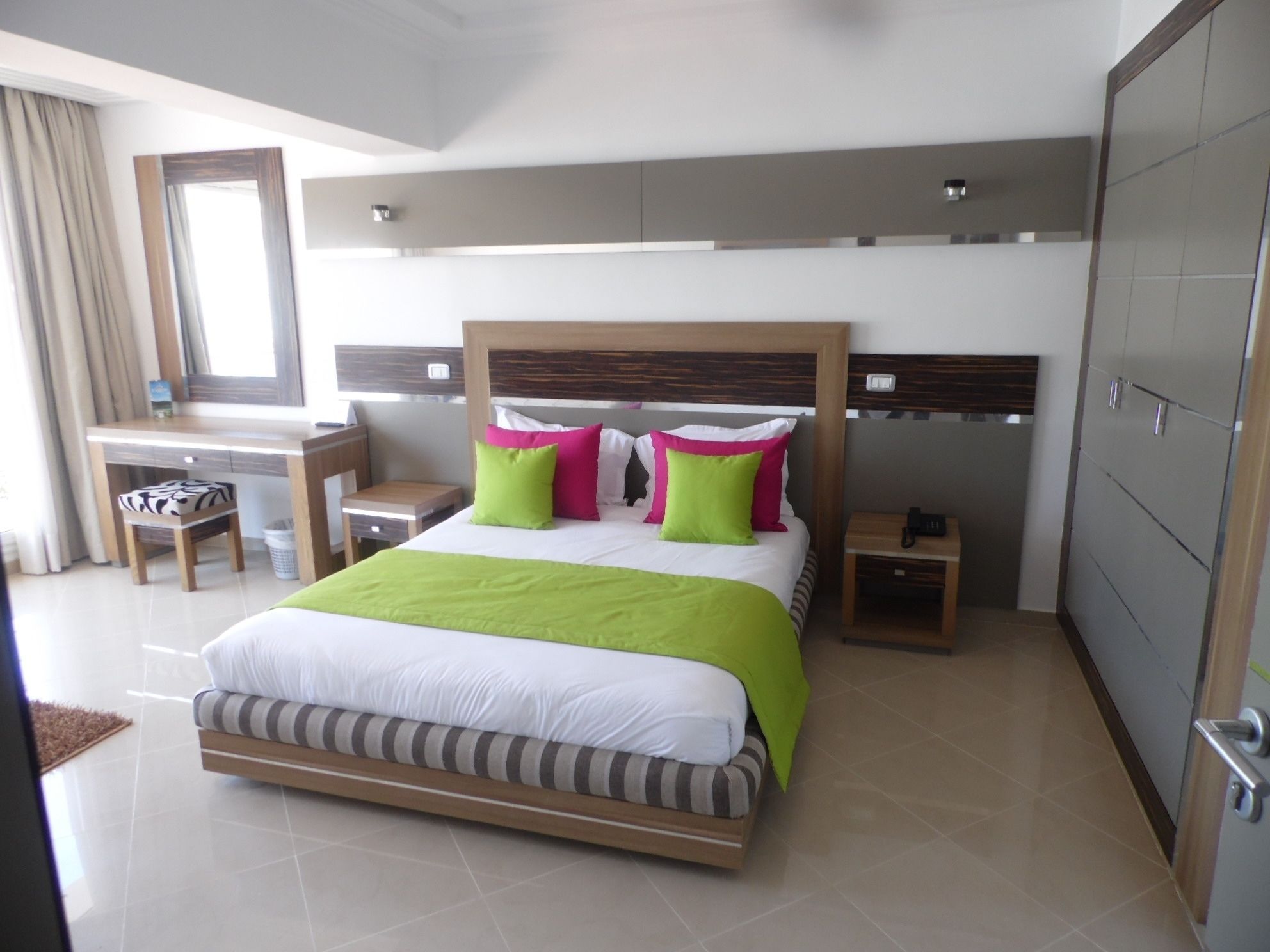 A modern hotel room with a large bed, a desk, and a chair.
