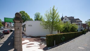 A modern hotel building with a unique spherical structure, a cobblestone pathway, and a clear view of the surrounding urban area. - Hotel Wiehberg (Hannover)