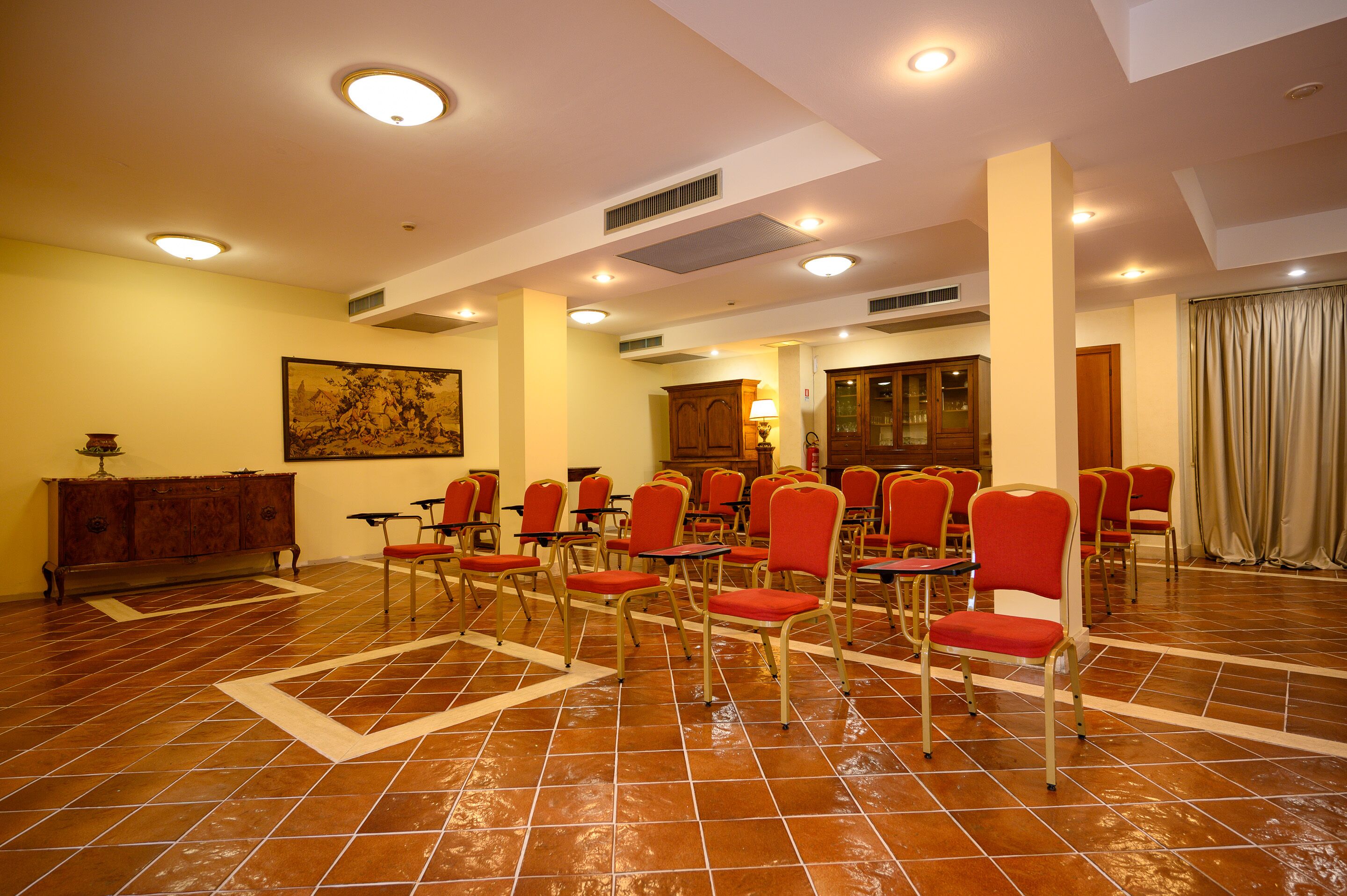 A conference room with red chairs, a wooden cabinet, and a painting on the wall.