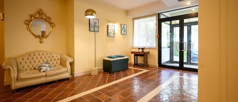 Una habitación amplia con un ventanal grande, un sofá, un banco y un espejo en la pared.