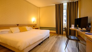 A hotel room with a bed, a desk with a chair, a television, and a window with curtains. - Hotel Torre di Pratolungo (Rome)