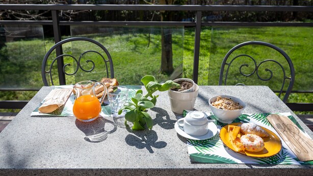 A table set outdoors with breakfast items including toast, juice, a plant, a bowl of cereal, a teapot, and a plate with pastries. - Hotel Torre di Pratolungo (Rome)