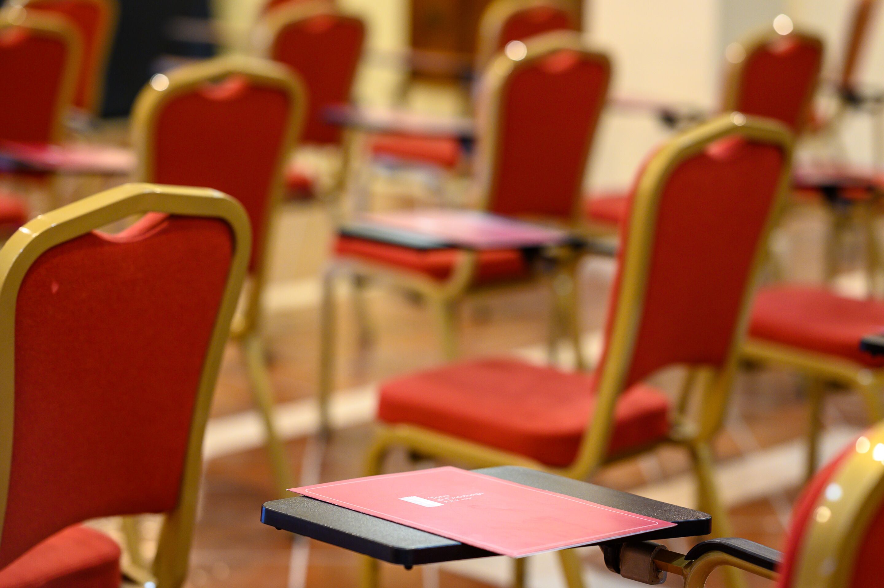 Rows of red chairs with gold frames and black tables, suggesting a formal dining or meeting area.