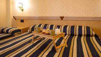 Una habitación de hotel con una cama, una mesita de noche y una lámpara de pared.