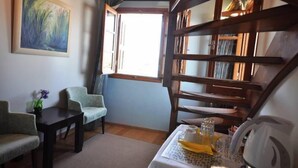 A room with a large window, a painting on the wall, a table with a kettle, and two chairs. - Nikolaos Pension (Nafplio)
