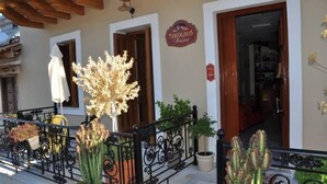 A building with a wooden pergola, a sign reading "Nikolaos Restaurant," and a black wrought iron railing with potted plants. - Nikolaos Pension (Nafplio)