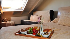 A neatly made bed with a tray of breakfast items including fruits, bread, and a vase with flowers. - Nikolaos Pension (Nafplio)