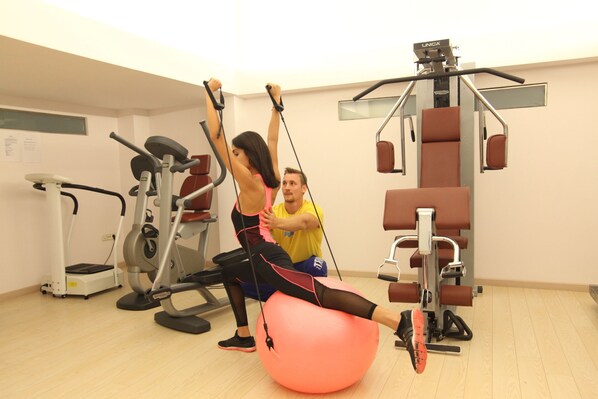 Un gimnasio con equipamiento de ejercicio, que incluye una máquina de remo y una bicicleta estática.