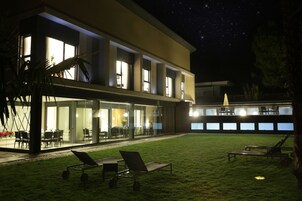 Un edificio moderno con amplios ventanales, un césped y asientos al aire libre.