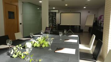 A conference room with a long table, chairs, a projector screen, and a whiteboard.