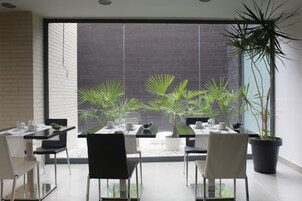 Un comedor moderno con pared de ladrillo, ventanas amplias y plantas en macetas.