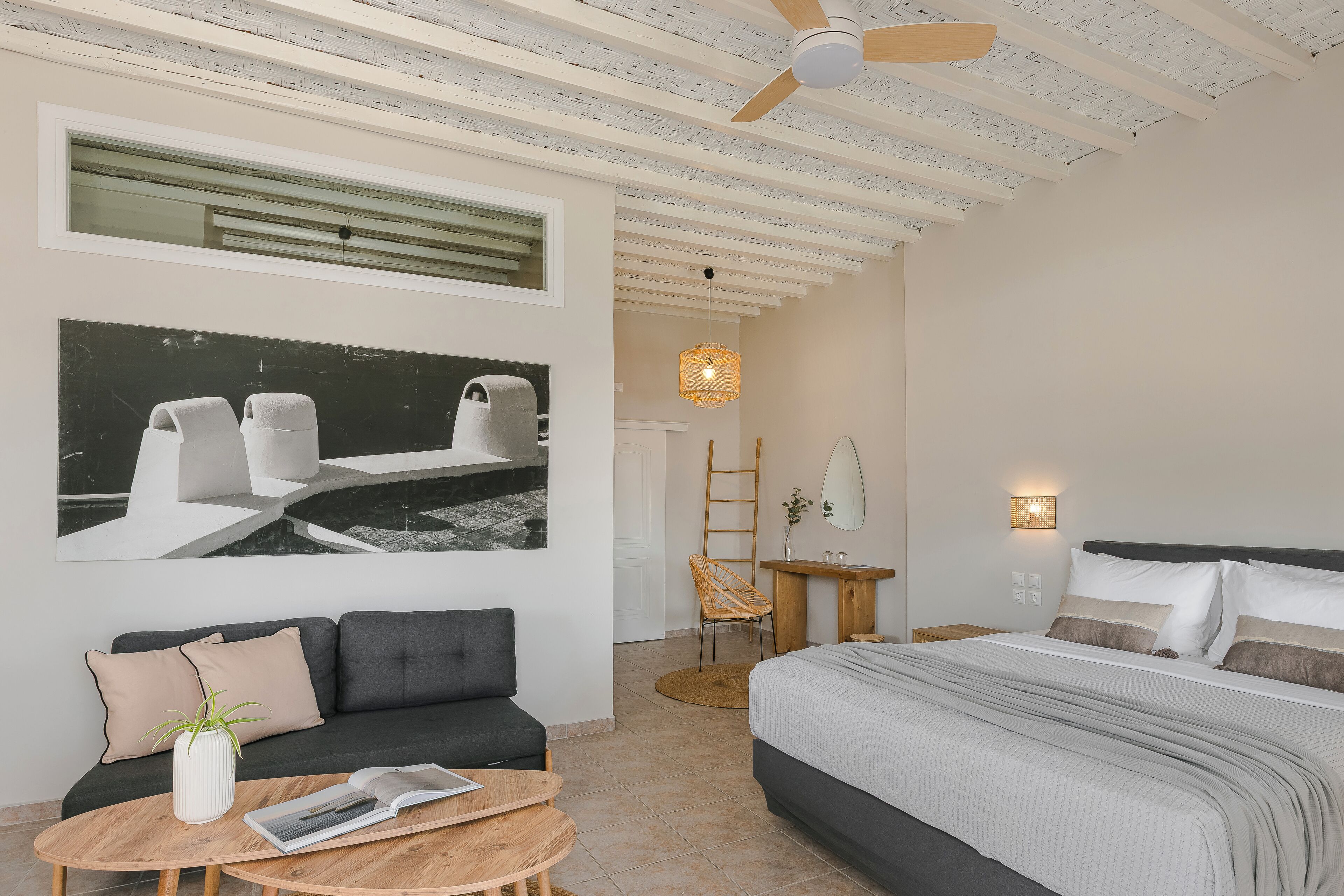 Une chambre à coucher moderne avec un lit, un canapé, une table basse et un tableau au mur.