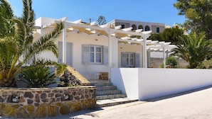 Un edificio blanco con pared de piedra y palmeras.