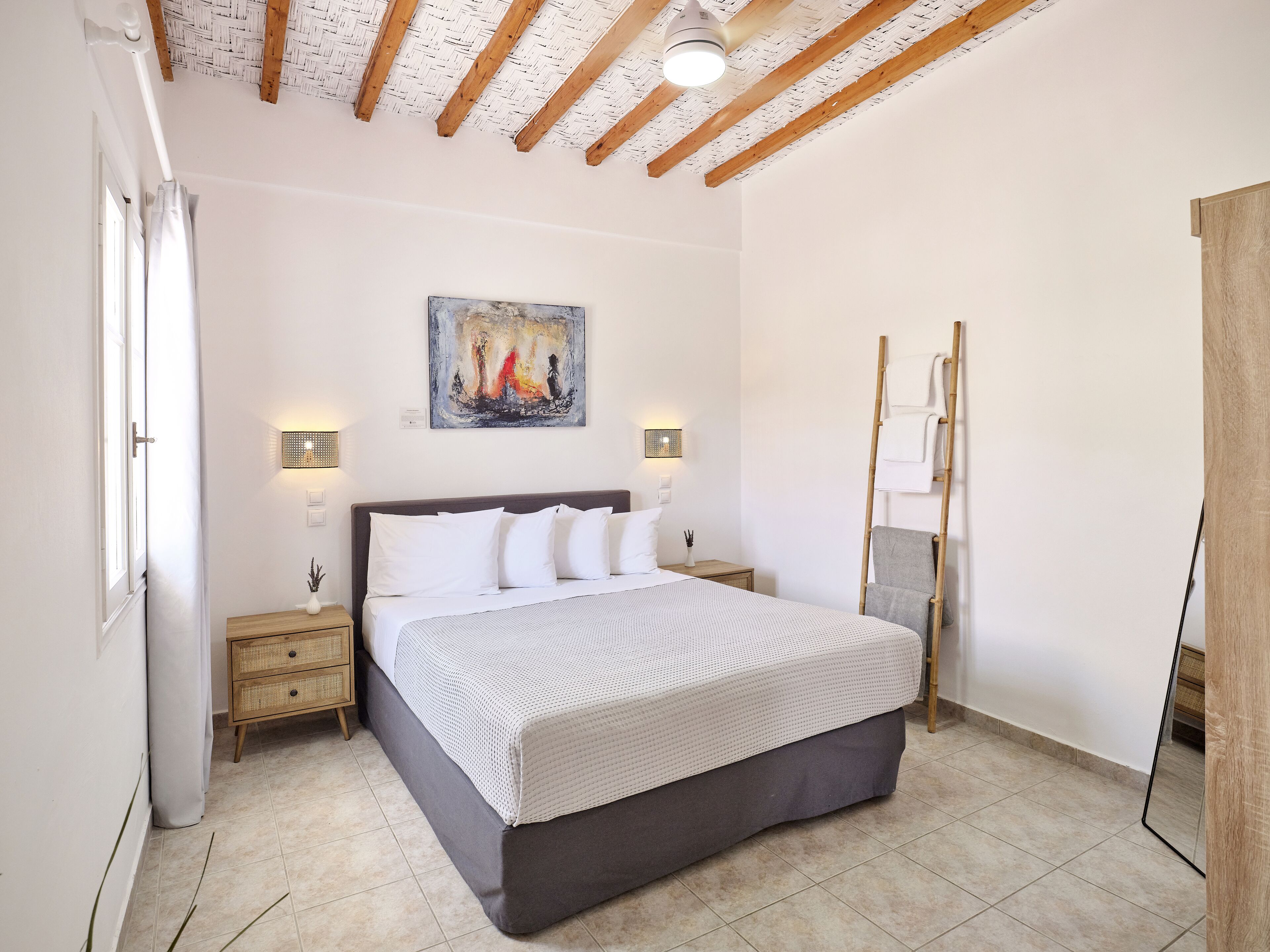 Un dormitorio con cama, mesitas de noche, un cuadro y una escalera.