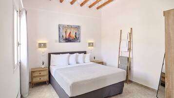 Un dormitorio con cama, mesitas de noche, un cuadro y una escalera.