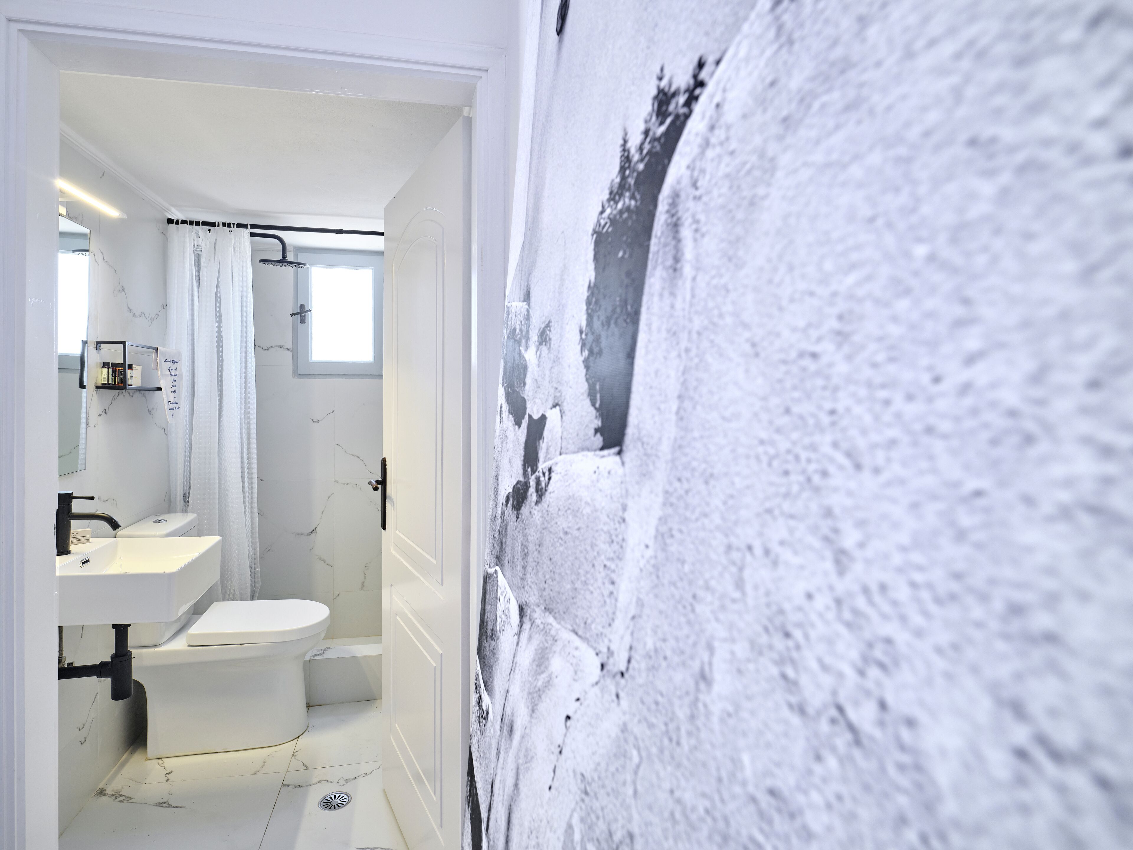 Un bany amb un lavabo blanc, vàter i zona de dutxa.