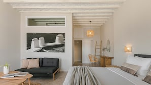 Un dormitorio moderno con cama, sofá, una mesita y una silla.