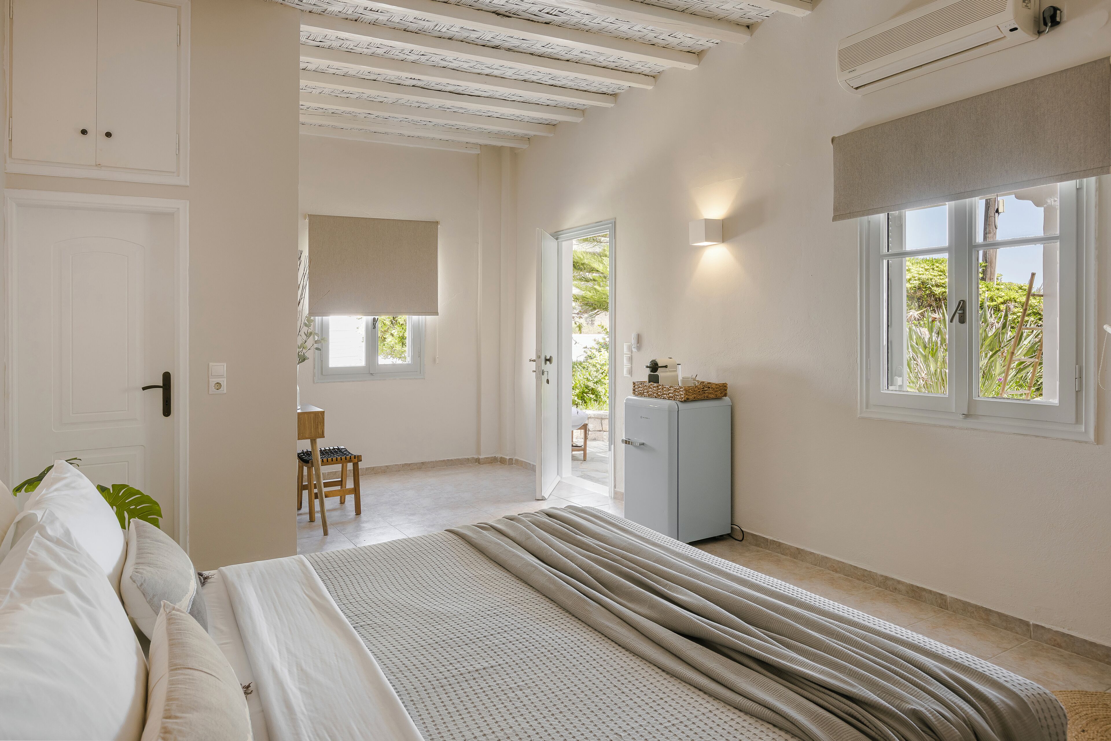 A bedroom with a bed, a desk, and a window.