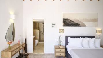 Een slaapkamer met een bed, nachtkastjes, een spiegel en een badkamer zichtbaar door een geopende deur.