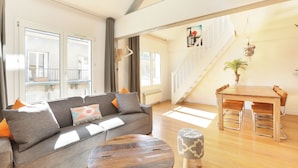 A spacious living area with a grey sofa, wooden coffee table, and a dining table with chairs. -  Les Lilas Serviced Apartments (Les Lilas)