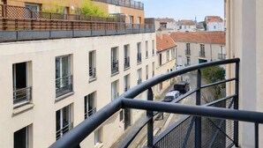 A multi-story building with balconies, a clear sky, and a street view. -  Les Lilas Serviced Apartments (Les Lilas)