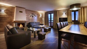 A modern living room with a fireplace, leather sofas, a dining table, and a TV.