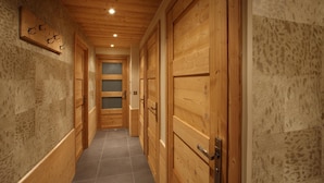 A wooden hallway with a tiled floor, wooden doors, and a wall-mounted coat rack.