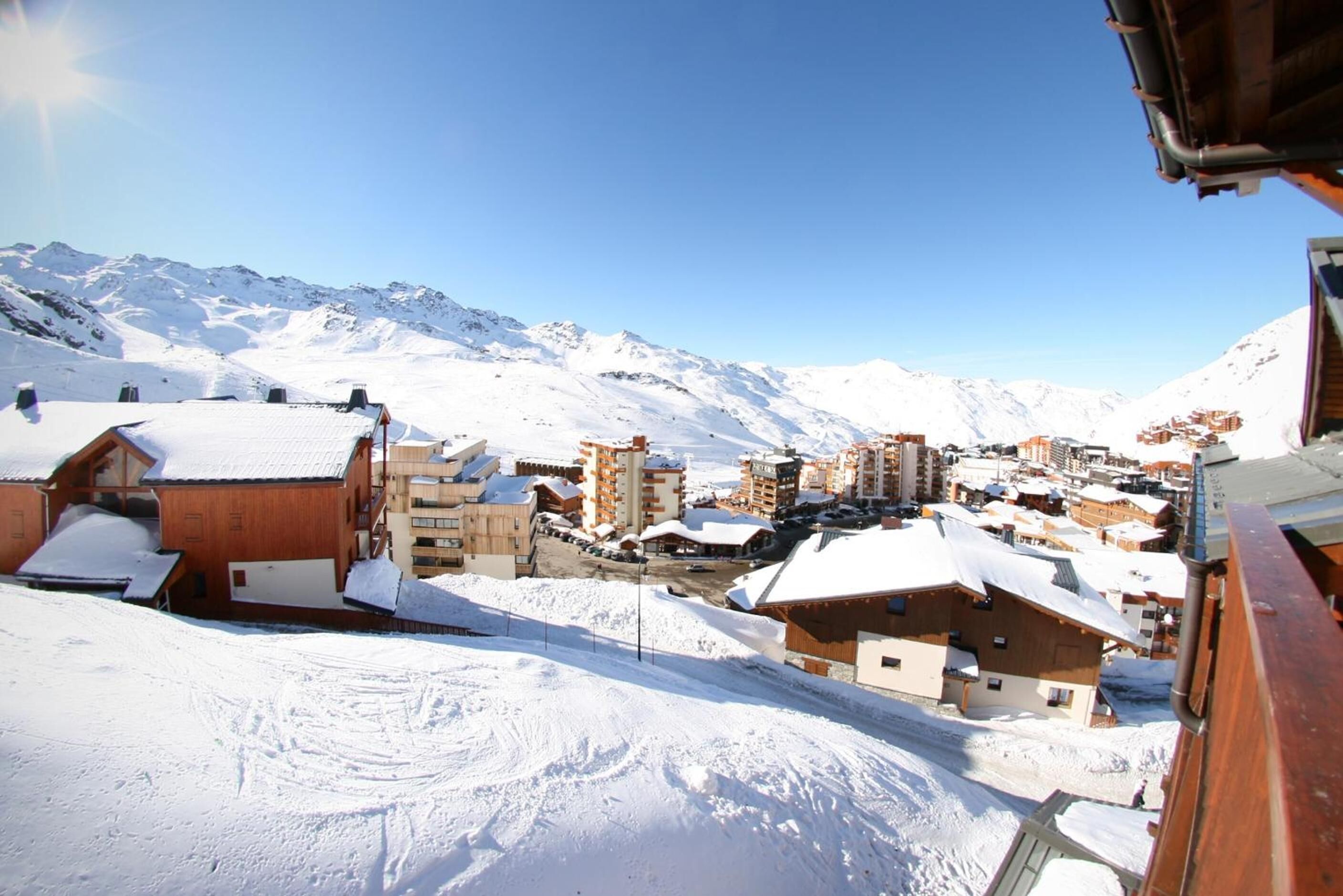 Une ville de montagne enneigée, avec des bâtiments en bois et une vue dégagée sur les montagnes en arrière-plan.