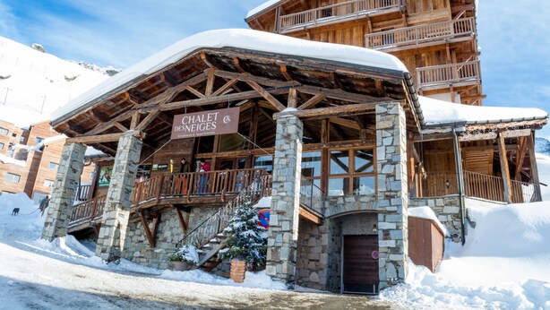 A chalet-style building with stone pillars and wooden balconies, labeled as a chalet and restaurant.