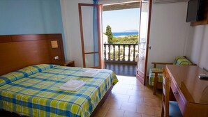 A hotel room with a bed, a desk, and a balcony with a view of the sea. - Navarone (Pylos-Nestoras)