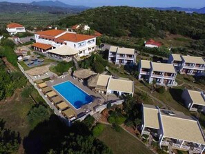 An aerial view of a resort with multiple buildings, a swimming pool, and lush greenery. - Navarone (Pylos-Nestoras)