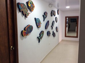 Un pasillo con varias obras de arte abstractas y coloridas en la pared.