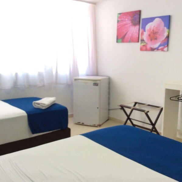 A hotel room with two beds, a small refrigerator, and a window with curtains. - La Posada de Lulu (San Andrés)