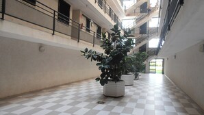 A spacious indoor area with a checkered floor, multiple balconies, and potted plants. - Apartamentos Surfing 3000 (Peniscola)