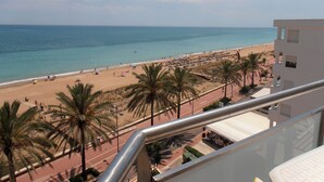 A beach view from a balcony with palm trees and a clear sky. - Apartamentos Surfing 3000 (Peniscola)