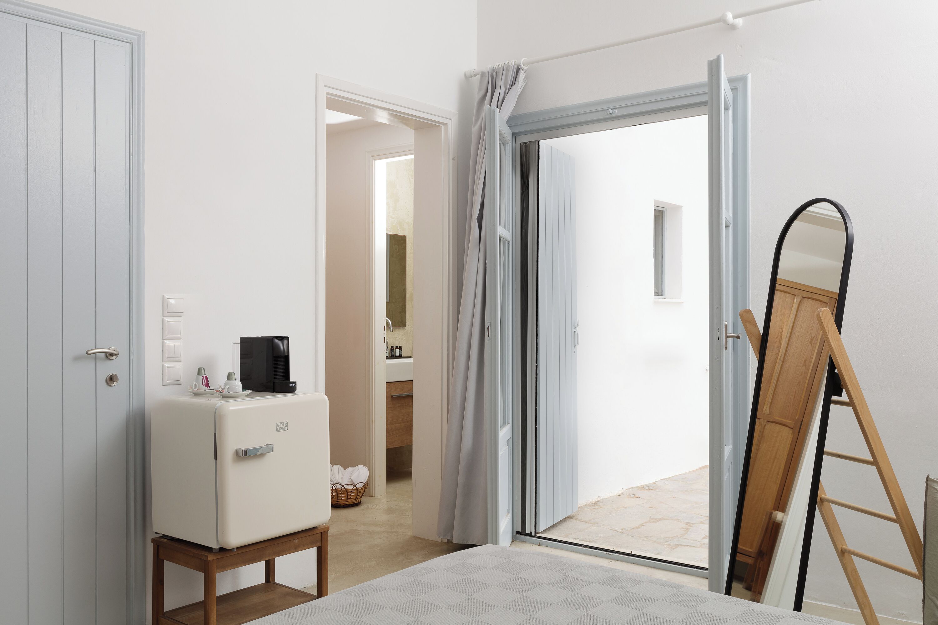 A room with a white refrigerator, a wooden ladder, and a sliding glass door leading to an outdoor area.